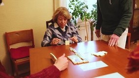 Elderly woman smiling while playing dominoes with her family, enjoying leisure time together - Powered by Shutterstock - Get 15% off with code: PIKWIZARD15