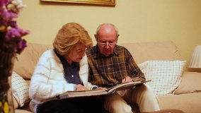 Happy retired couple enjoying their free time together, browsing through old photographs and reminiscing about past memories - Powered by Shutterstock - Get 15% off with code: PIKWIZARD15