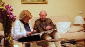 Happy retired couple enjoying their free time together, browsing through old photographs and reminiscing about past memories - Powered by Shutterstock - Get 15% off with code: PIKWIZARD15