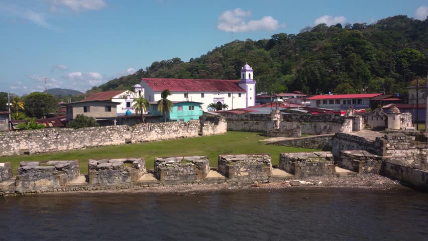 Portobelo, Panamá. March 17 of 2025. You can see the walls and canons of the ancient Spanish colonial settlement of "Fuerte San Jerónimo" in Portobelo. Aerial 4k drone shot. You an see fishing boats.