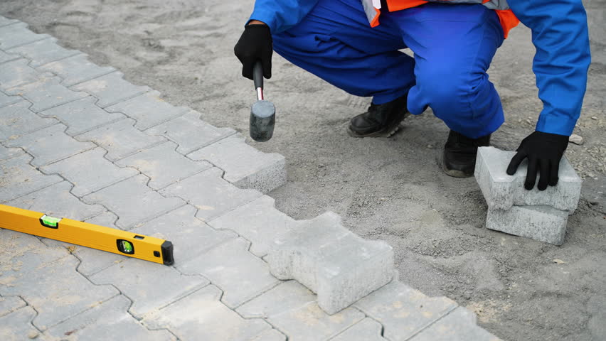 Worker laying interlocking paving stones on a construction site