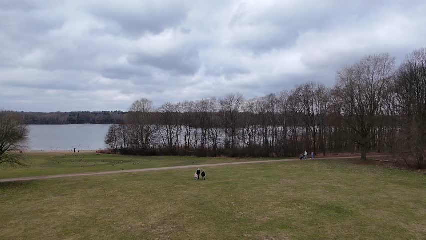 Drone camera glides over lush green expanse and lake waters, revealing the park