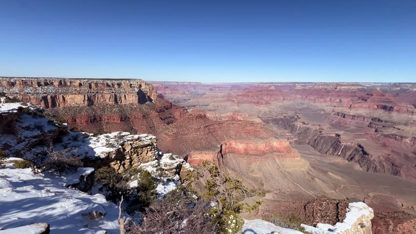 A breathtaking panoramic view of the Grand Canyon in the winter season, showcasing its deep canyons and beautiful snow
