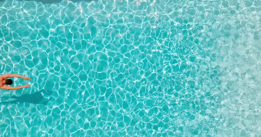 Aerial view as a man dives into the pool and swims. Slow motion