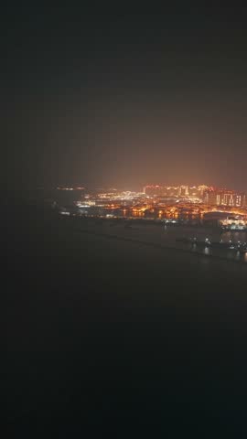 The skyline of the Lusail area from top in Doha, Qatar. Illuminated modern skyscrapers aerial view from rooftop at night. Parks and traffic on the road.