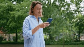 Woman enjoy video phone conversation walking urban park closeup. Smiling female talking cellphone on green street. Carefree lady greeting smartphone strolling city area alone. Communication concept  - Powered by Shutterstock - Get 15% off with code: PIKWIZARD15