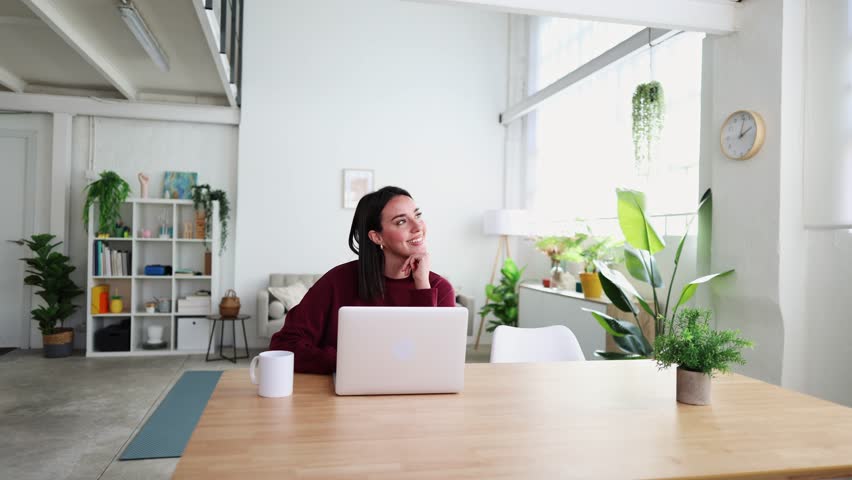 Young woman smiling and working on laptop at home