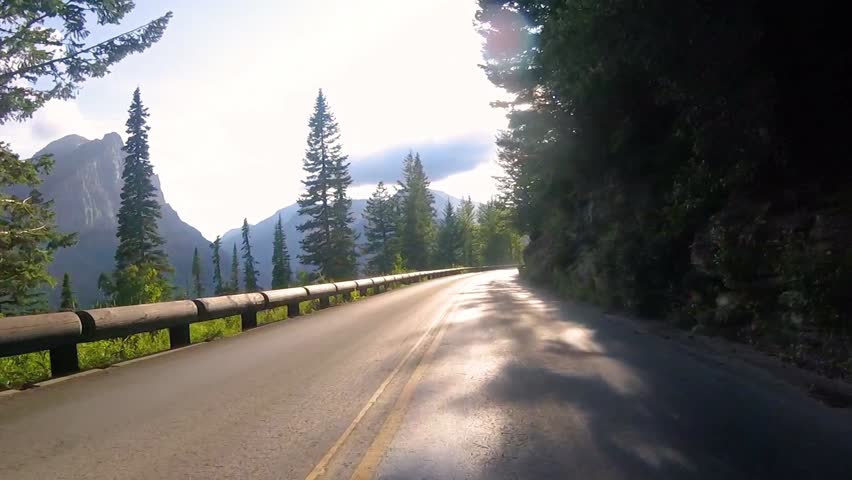 Driving into the blinding sun on Going To The Sun Road during summer in Glacier National Park, Montana, USA