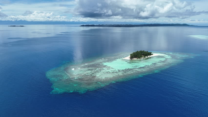 An idyllic, tropical island is surrounded by healthy coral reef in the Togian Islands of Indonesia. This equatorial area is part of the Coral Triangle and harbors incredible marine biodiversity.