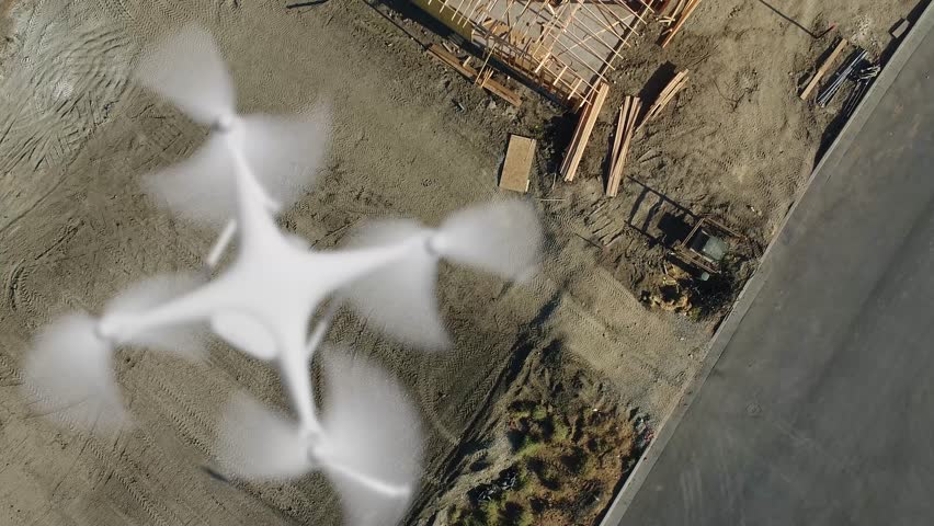 Aerial Angle Above A UAV Quadcopter Drone Flying Slow Motion Outdoors Above A Housing Construction Site.