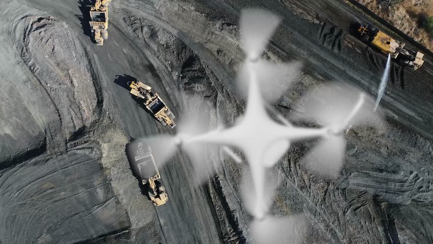 Aerial Angle Above A UAV Quadcopter Drone Flying Slow Motion Outdoors Above A Construction Site With Excavation Grading Equipment.