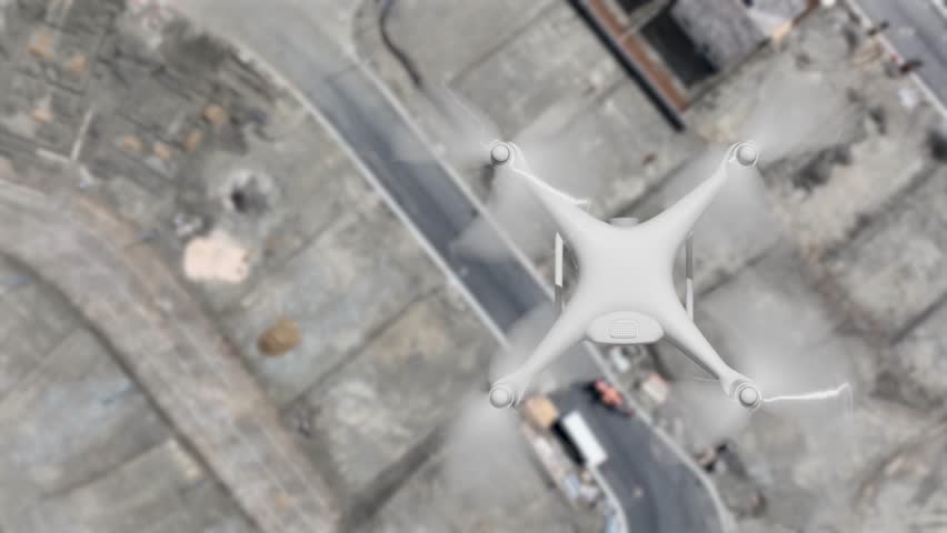 Aerial Angle Above A UAV Quadcopter Drone Flying Slow Motion Outdoors Above A Housing Construction Site.