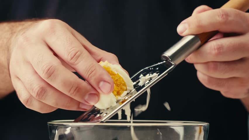 Grater and eggs, woman grates boiled egg for salad, cooking food.