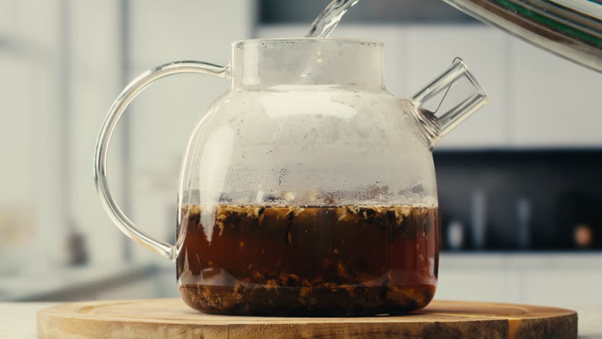 Ginger tea, freshly brewed black organic herbal tea with ginger, mint and lemon in a glass teapot, medication healthy.