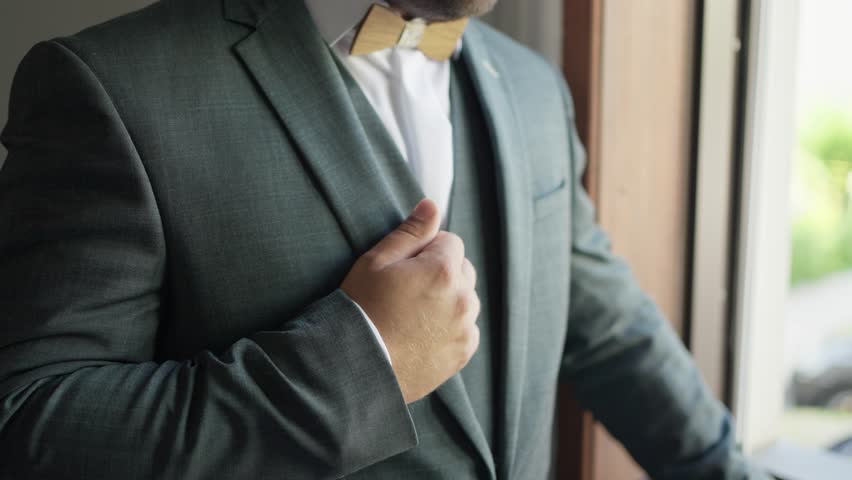 Groom in elegant suit adjusting lapel, preparing for his wedding day