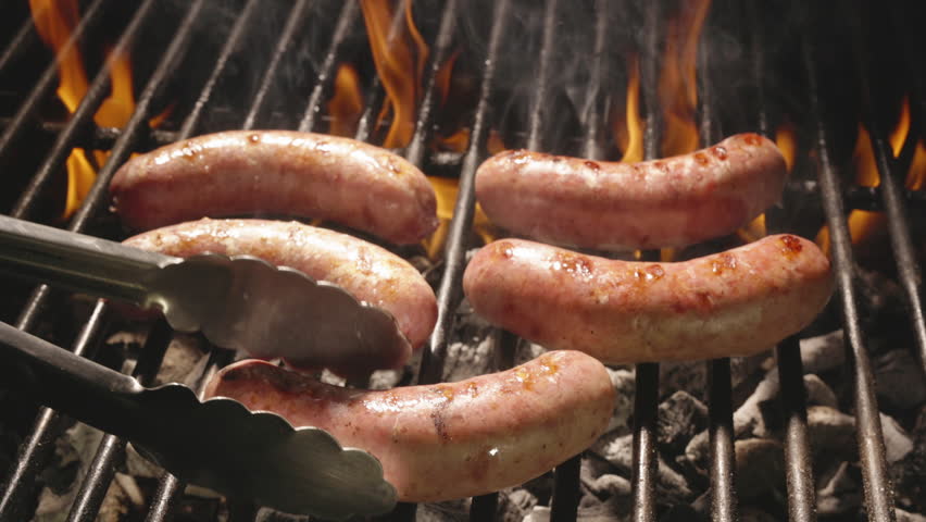 Juicy sausages sizzle on grill under flames. Cook expertly flips sausages with tongs. Their smoky sweetness and delicate texture make them perfect addition to any grilled feast. Template for title