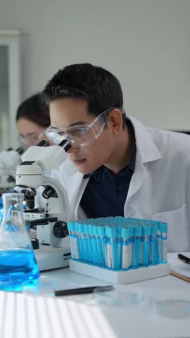 Young scientist wearing lab coat, gloves and protective glasses, performing various tasks including using microscope, examining test tubes, and taking notes on a clipboard