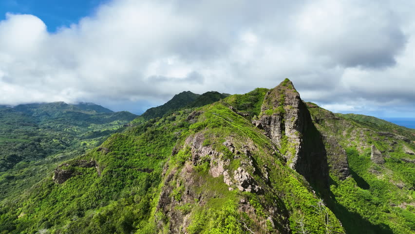 Drone flying along a mountain range on the Nā Pali Coast, in sunny Kauai, Hawaii