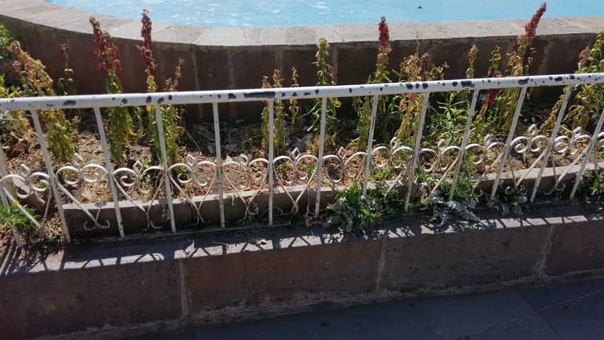 Tilt-up shot of an empty fountain in a park, La Paccha, surrounded by streets and buildings in the background in Cusco, Peru, on a beautiful sunny day.