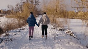 Young couple walking hand in hand by a frozen lake, wrapped in a cozy blanket, enjoying a peaceful winter day with a scenic church in the background. High quality 4k footage - Powered by Shutterstock - Get 15% off with code: PIKWIZARD15