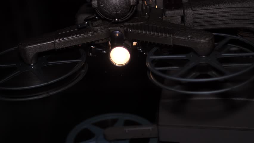 Detailed shot of a historic cinema projector reel spinning slowly, showcasing the intricate texture and mechanical movement of traditional film projection.