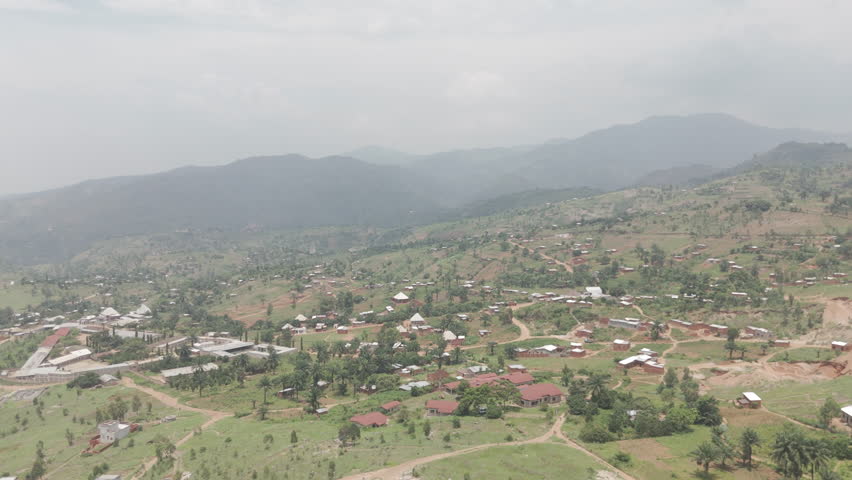 Drone shot the rural town of Kimina Bujumbura Burundi Africa on a warm day with houses on the ground and Lake Tanganyika in the background behind the hills LOG