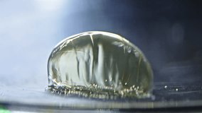 A close-up of a water droplet forming, with light reflections and ripples in the liquid - Powered by Shutterstock - Get 15% off with code: PIKWIZARD15