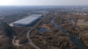 Aerial view drone perspective of large warehouse data centres surrounded by green land and rivers in England. Future technology and business developments greener future. - Powered by Shutterstock - Get 15% off with code: PIKWIZARD15