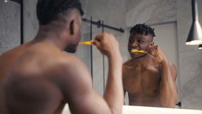 Fit African American man brushing his teeth in front of a mirror, dental hygiene - Powered by Shutterstock - Get 15% off with code: PIKWIZARD15