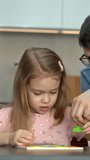 Father and little girl put together colored tangram puzzle. Family spends leisure time collect wooden jigsaw. Education concept. Vertical shot - Powered by Shutterstock - Get 15% off with code: PIKWIZARD15
