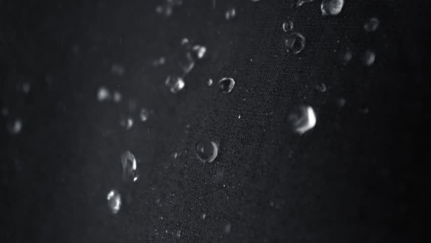 Super Slow Motion Detail Shot of Water Flow Down on Waterproof Black Cloth at 1000fps.