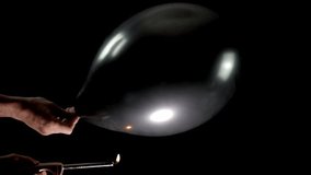 Watch in slow motion as a black balloon is held by one hand, while another hand introduces a small fire. The intense moment captures the balloon popping in a dramatic burst of air and tension. - Powered by Shutterstock - Get 15% off with code: PIKWIZARD15