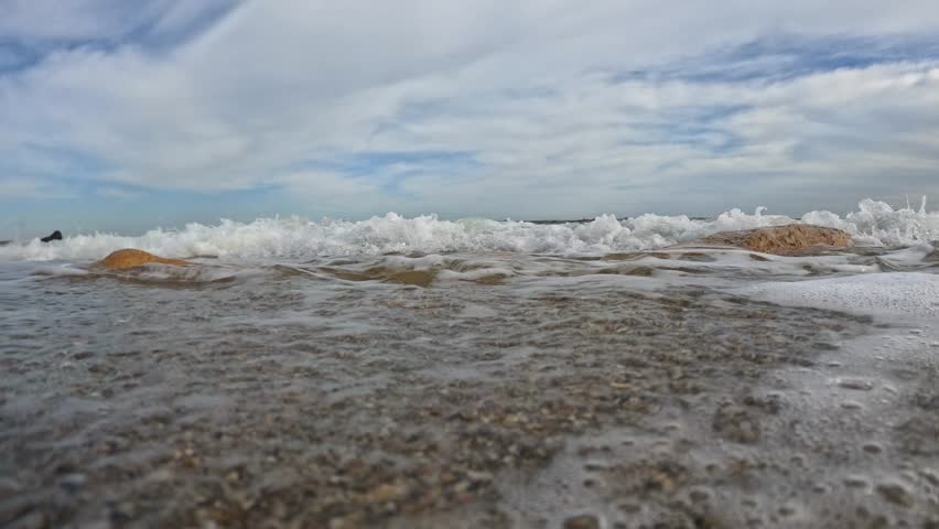 Hydrodynamics of a sandy shore, sand and pebbles move in the waves on the beach in the Black Sea, Odessa