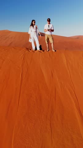 Vertical aerial view of Deadvlei in the southern Namib Desert near Sesriem, part of Sossusvlei National Park in Namibia. Surrounded by towering dunes, people are climbing the Big Daddy dune at sunrise
