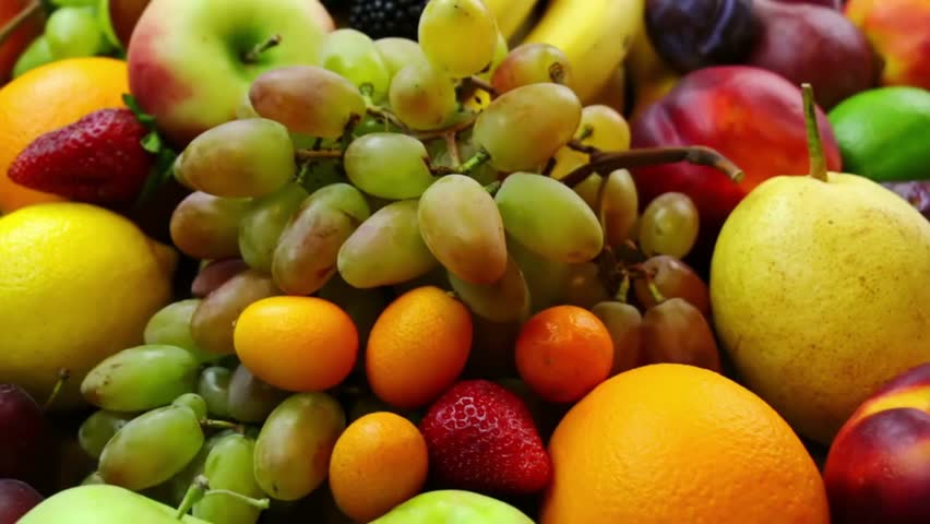 Close-up shot of a vibrant assortment of fresh fruits, including apples, bananas, grapes, berries, plums, and citrus fruits.