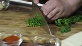 Close-up of a chef's hands finely chopping fresh parsley and chives on a wooden cutting board. - Powered by Shutterstock - Get 15% off with code: PIKWIZARD15