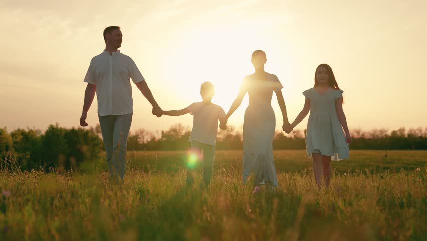 Cute happy family. Parents children in park at sunset. Family walking on green grass in nature park. Family fun, daughter son parents in nature. Active young family on lawn in summer. Happy people sun