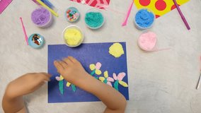 Child making flower from plasticine and paper and beads. Simple crafts. Preschool. Early development concept. Sensory perception. Educational and entertaining classes. Hobby, DIY. - Powered by Shutterstock - Get 15% off with code: PIKWIZARD15