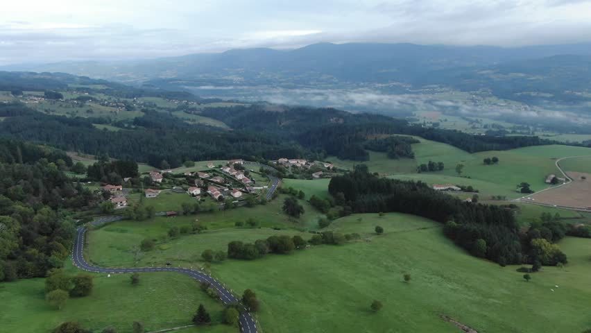 Village surrounded by green hills, French countryside Ambert, France. Aerial drone panoramic view