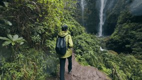 Female hiker in reaching base of tropical waterfall throwing hands up, explore of Madeira - Powered by Shutterstock - Get 15% off with code: PIKWIZARD15