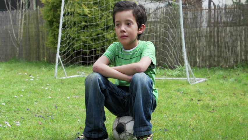 Sad boy sitting on soccer ball