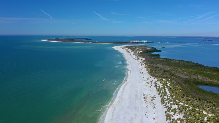 A stunning aerial perspective of Caladesi Island, featuring its long stretch of untouched white sand beaches and clear blue waters.The vibrant coastline and lush vegetation highlight Florida’s beauty.