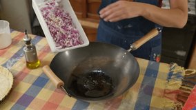 Experienced home cook carefully adding freshly chopped red onions from white container into sizzling hot wok, preparing traditional homemade meal with precise culinary technique - Powered by Shutterstock - Get 15% off with code: PIKWIZARD15