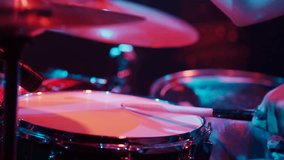 Close up slow motion of a drummer's hands hitting the snare drum during a live performance, illuminated by colorful stage lights - Powered by Shutterstock - Get 15% off with code: PIKWIZARD15