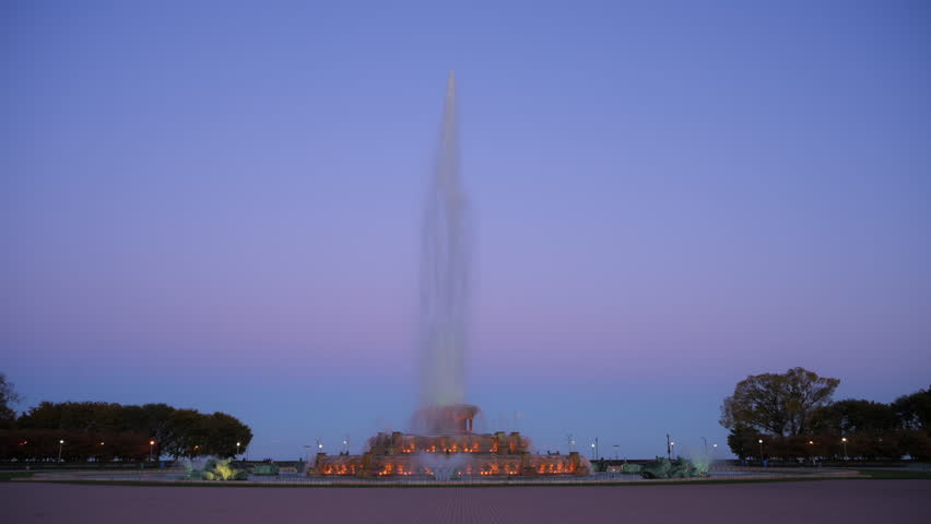 Evening view of Buckingham Fountain glowing with colorful lights against the Chicago skyline.