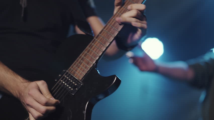 Professional guitarist performing dynamic electric guitar solo during energetic rock concert, capturing passionate musical expression in dramatic slow motion sequence