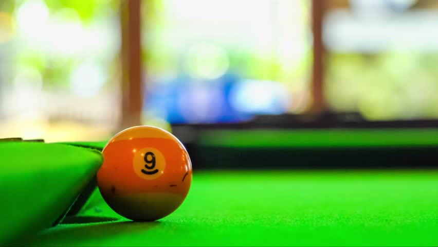 Close-up view of colorful billiard balls on a green pool table in a relaxed game setting with blurred background