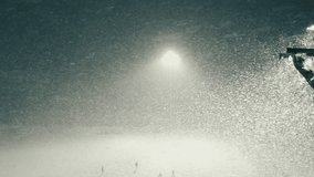 Circling aerial shot of stadium floodlight during snowfall blizzard. Stadium lighting illuminates falling snow while people are playing on football field. Spotlights illuminate the dark evening, night - Powered by Shutterstock - Get 15% off with code: PIKWIZARD15