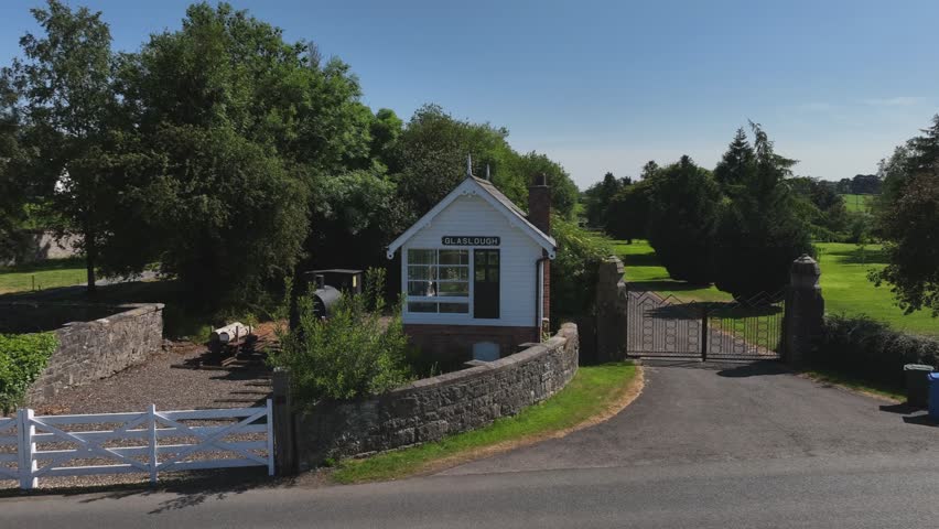 Old Signal Box, Glaslough, County Monaghan, Ireland, September 2022. Drone medium approach to the old Railway Building, passing over the road and former level-crossing fence surrounding the structure.
