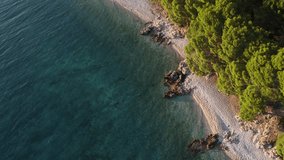 Wild beaches of Croatia. Rocky pebble beaches of Baska Voda. Pine trees on the seashore. Blue azure transparent water. Ecologically clean region. Adriatic coast. Tourists relax on the beach. - Powered by Shutterstock - Get 15% off with code: PIKWIZARD15